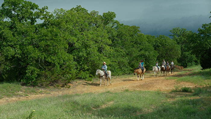 Group of people horseback riding on trail at Chickasaw Country riding stables